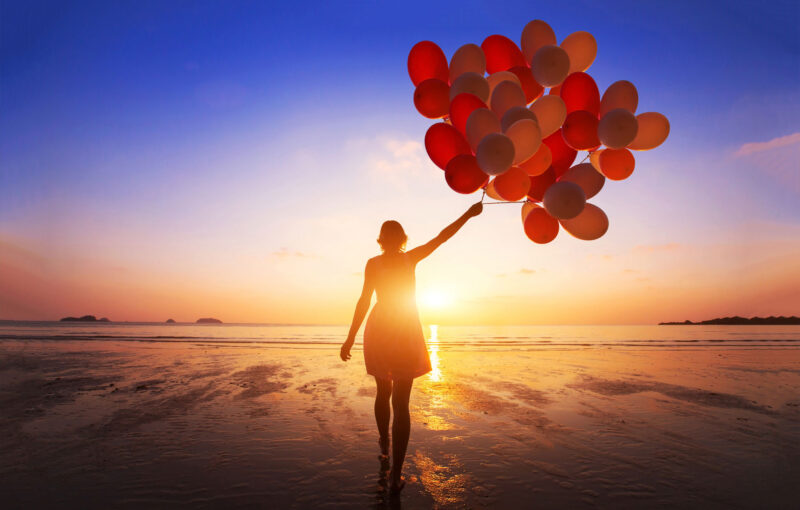 Woman with balloons on beach
